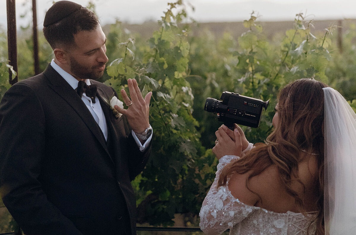 Bride filming groom with vintage Super 8 camera at a vineyard wedding
